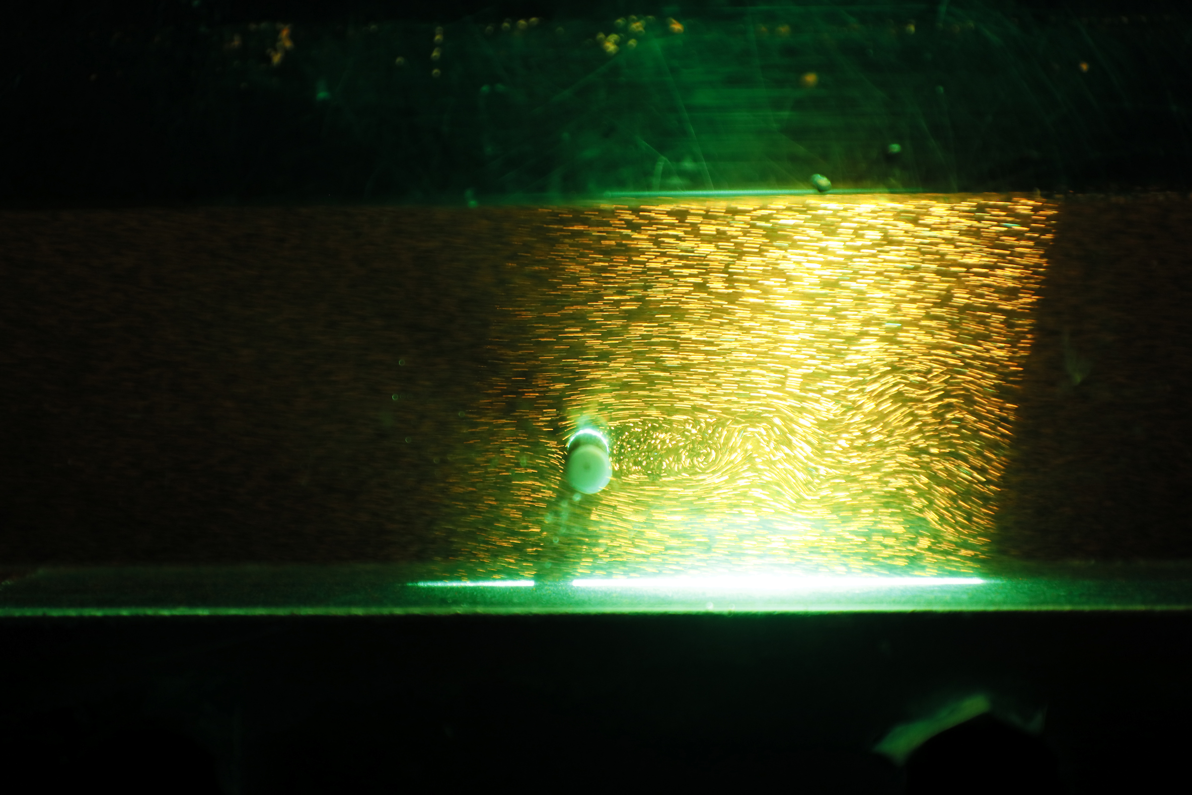 Bright sparks and green light illuminate a close-up of a welding process.