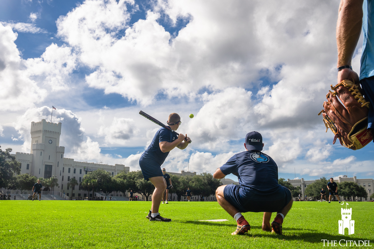 Players participate in a softball game on a campus field.