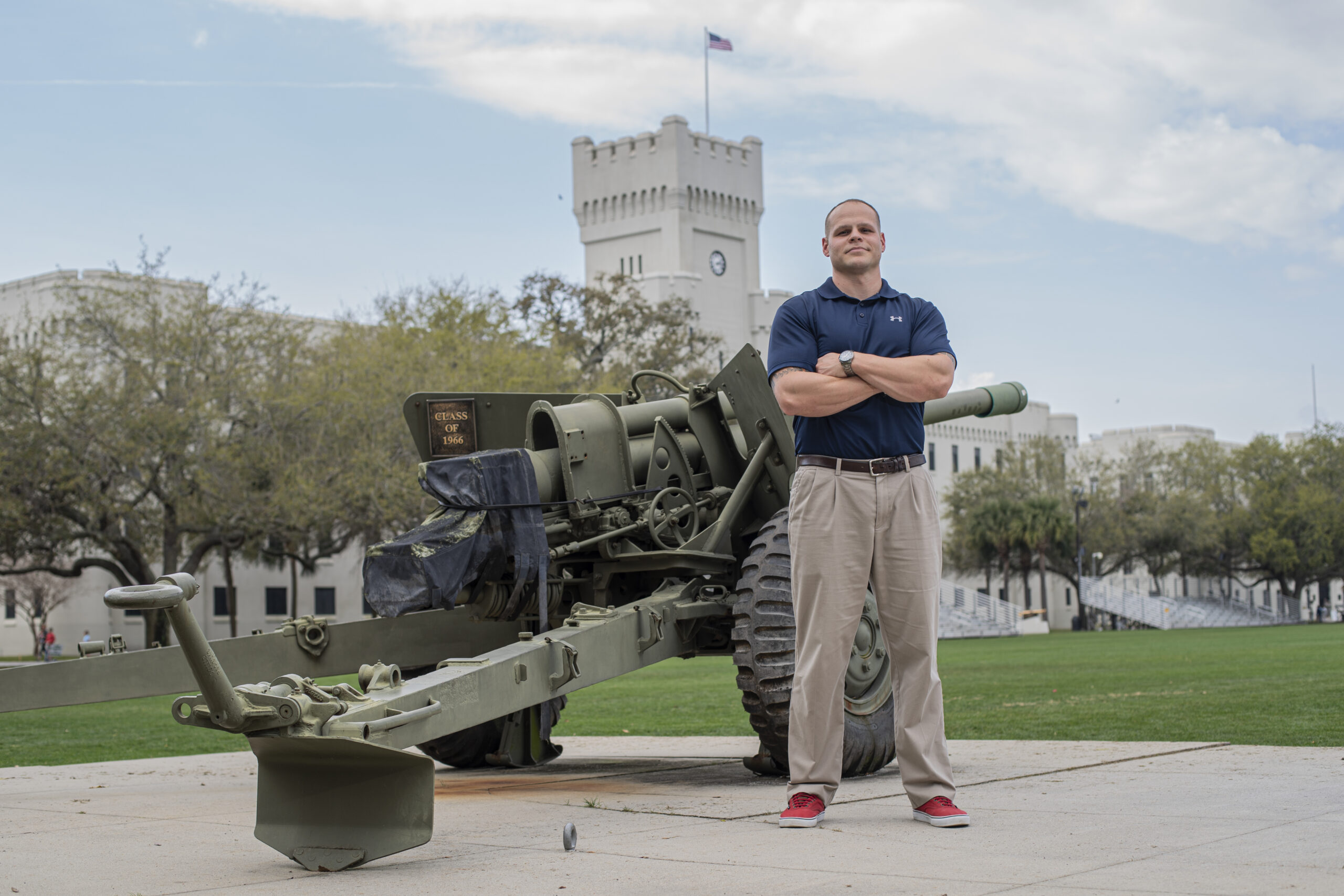 Man stands beside a historic artillery piece on The Citadel campus.