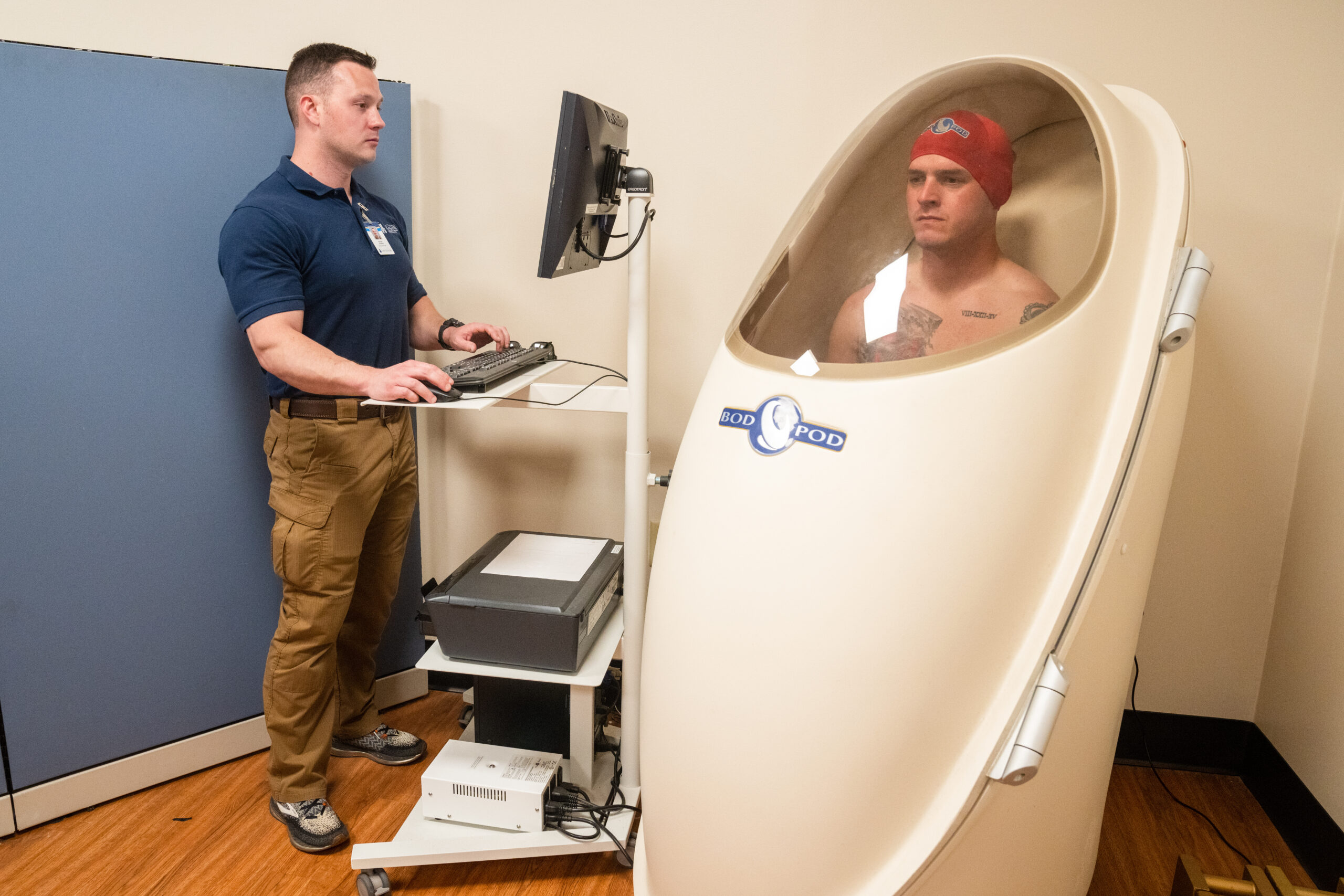 Participant undergoes body composition testing in a Bod Pod while a technician operates the computer.