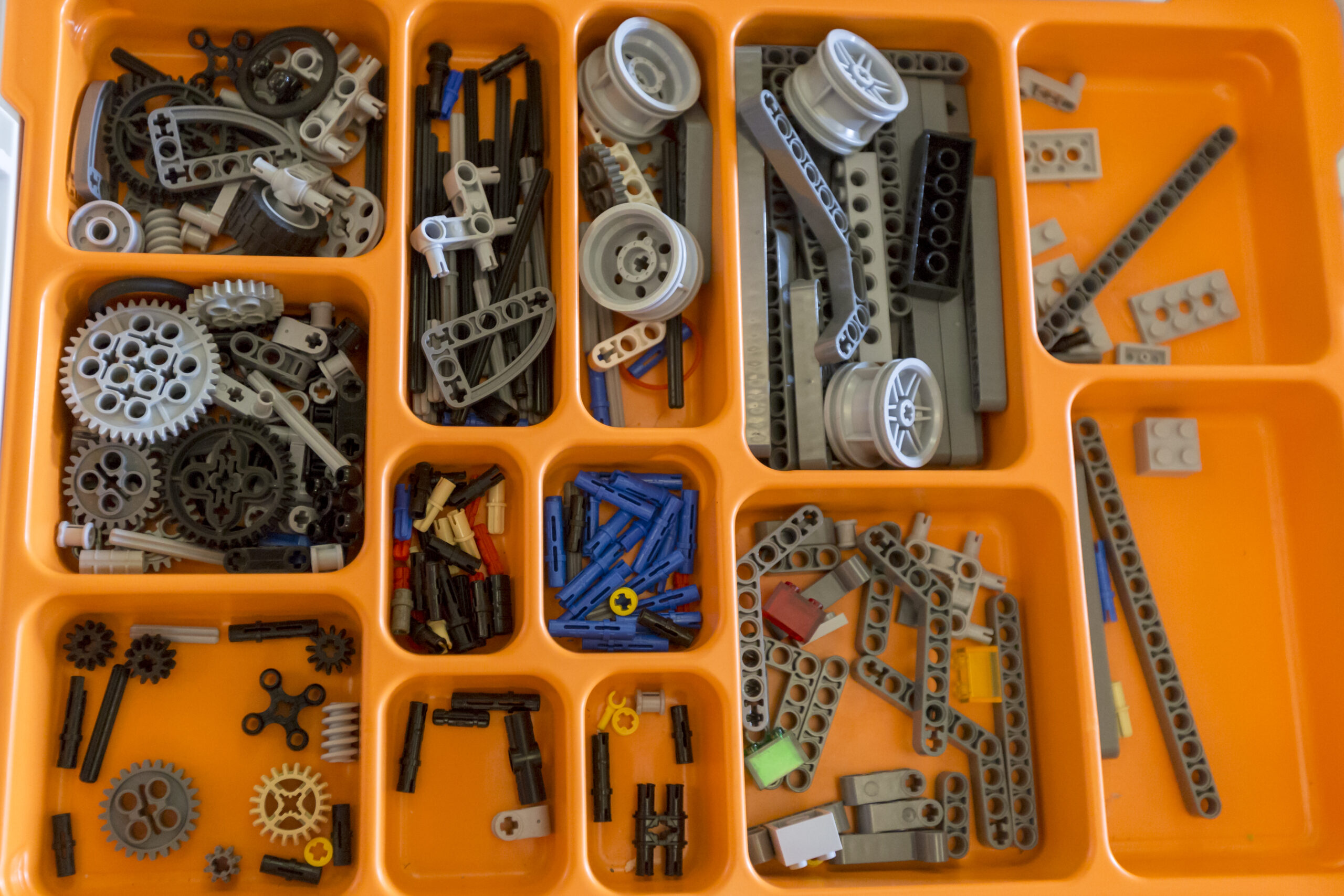 Assorted gears, wheels and building pieces organized in a robotics kit.