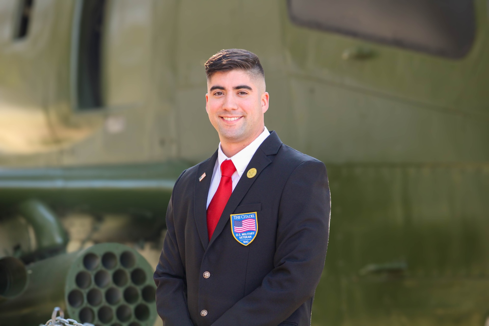 Veteran student wearing a Citadel U.S. Military Veteran blazer in front of a helicopter.