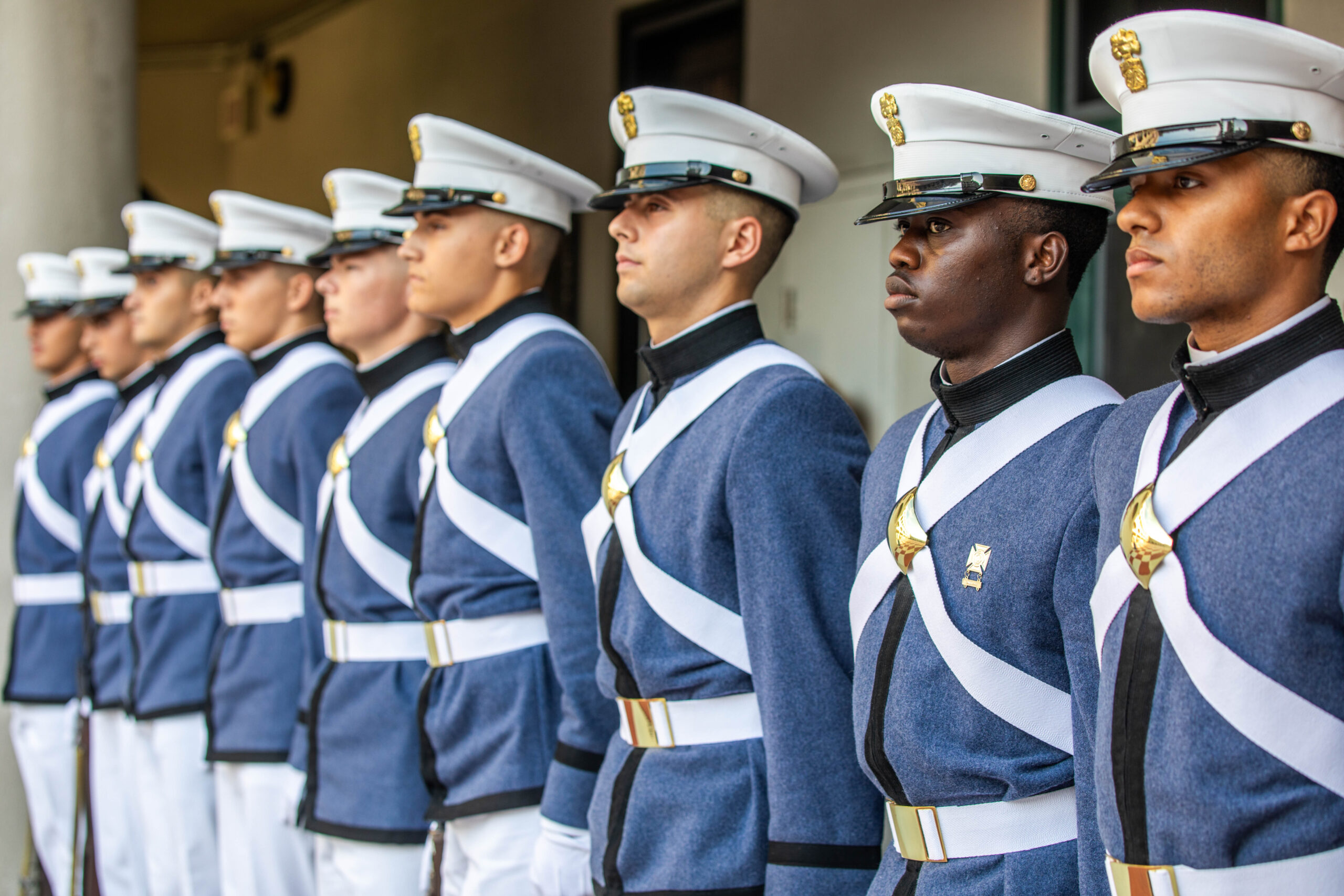 Row of Citadel cadets in dress uniforms and white caps stands at attention.